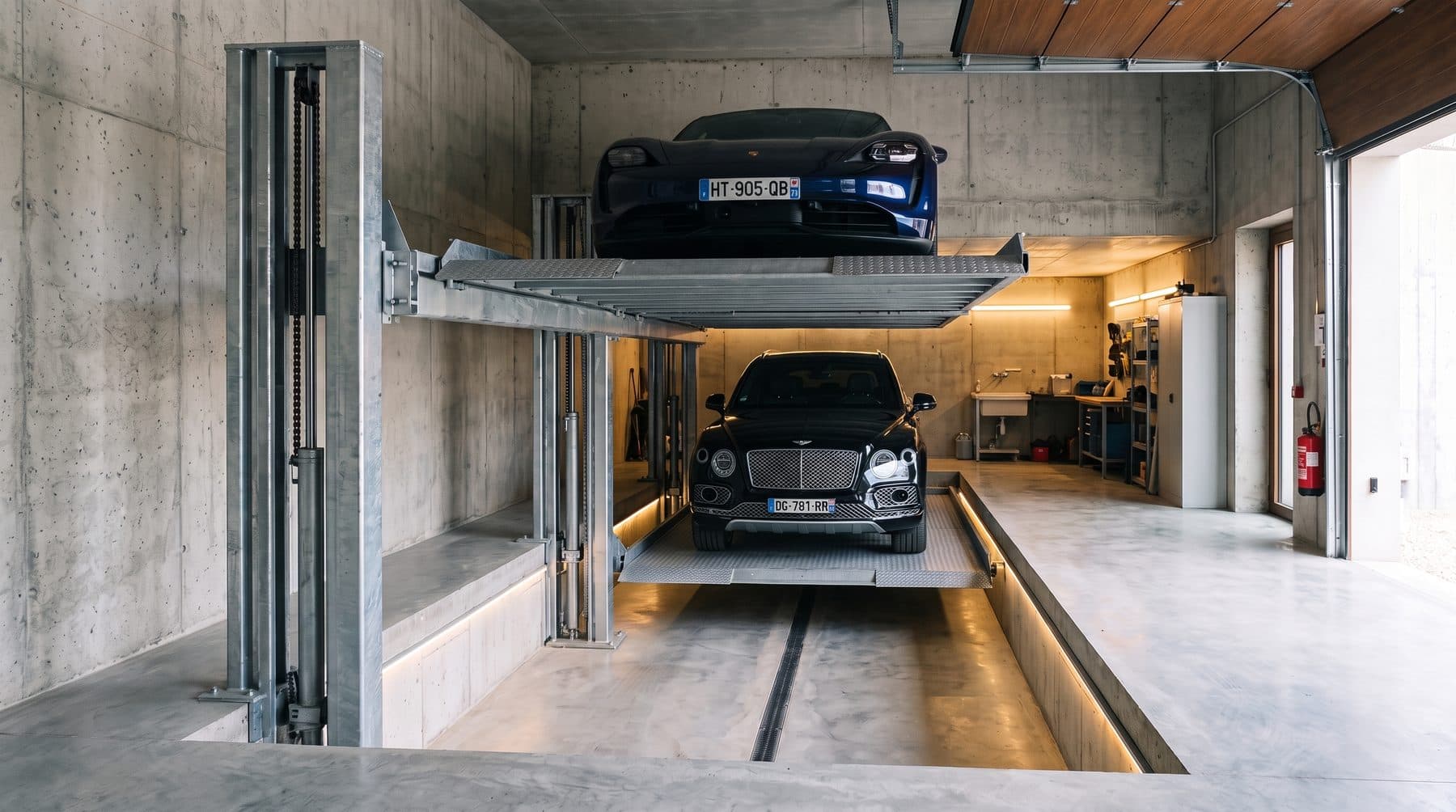 Doubleur de parking dans un garage béton, berline de sport sur le plateau haut et SUV de luxe sur le plateau bas descendu en fosse