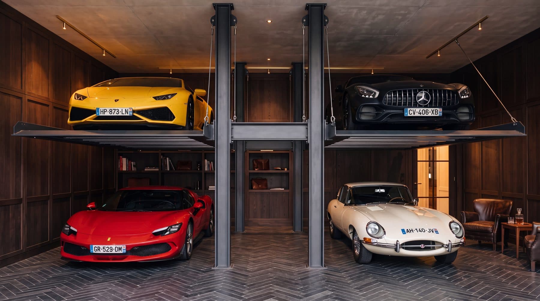 Quatre voitures de collection rangées sur deux niveaux d'une structure de stockage vertical en acier, dans un garage résidentiel lambrissé de chêne